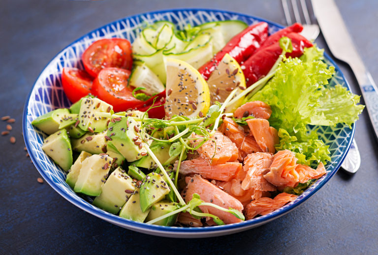 Healthy grilled salmon, avocado, tomato, cucumber, paprika and chia seeds. Balanced lunch in blue bowl. Buddha bowl.